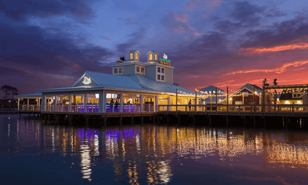 A serene night view of the pier in Myrtle Beach, illuminated by soft lights reflecting on the water.