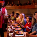A waitress dressed in pirate garb serves food to excited onlookers at the Pirates Voyage Dinner & Show in Pigeon Forge.