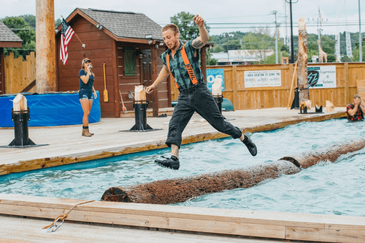 Lumberjack jumping off floating log at Paula Deen's Lumberjack Feud Show