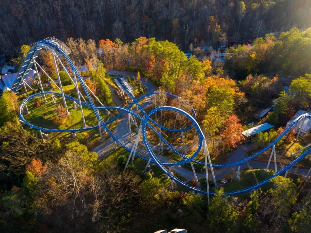 An overhead photo of a rollercoaster in a forest during an evening sunset.