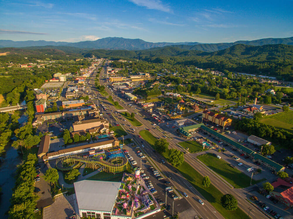 Aerial photo of the Pigeon Forge cityscape featuring tall buildings and a meandering river 