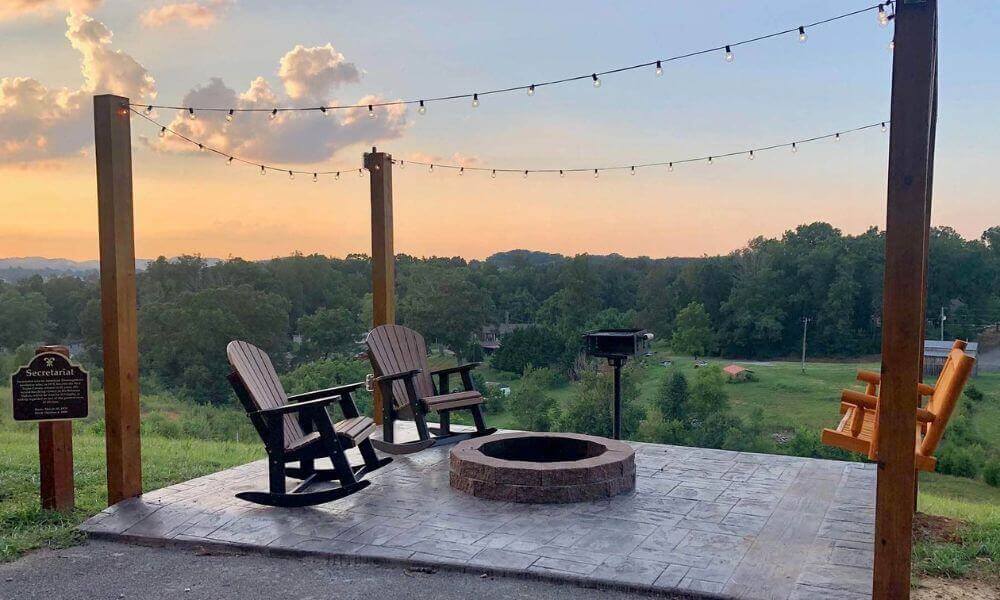 Outdoor chairs surround a fire pit at sunset.